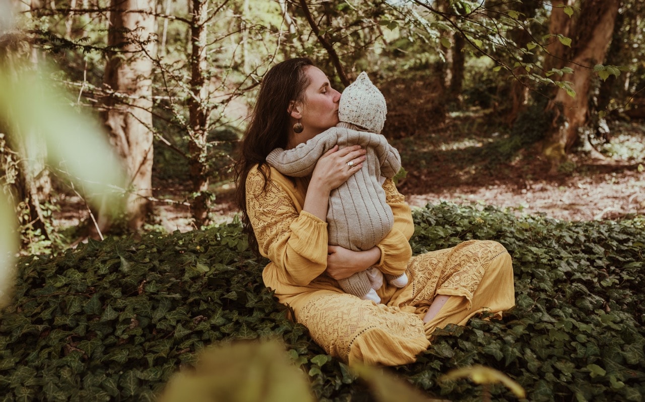 Barbora kissing her baby in a woodland